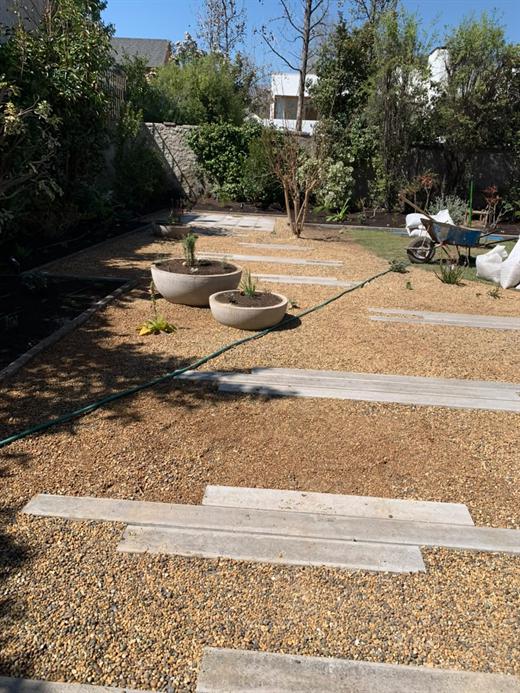 Jardín con gravilla, durmientes de concreto y maceteros